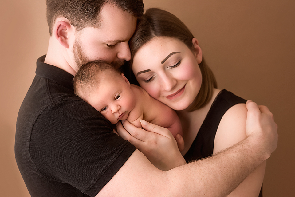 Portrait junger Eltern mit neugeborenem Baby auf dem Arm  